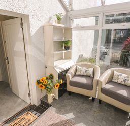 A conservatory with two chairs and a shelf at Hafan y Tyddyn