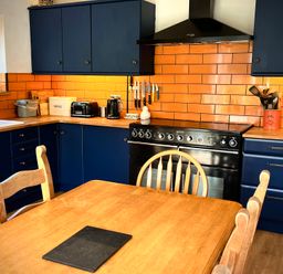 A kitchen with blue cabinets and wooden table at Ty Marlyn in St Davids