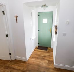 A hallway with a green door and wooden flooring at Doughbeg Beach Cottage