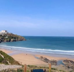 A beach with ocean waves and coastline at By The Sea in Newquay
