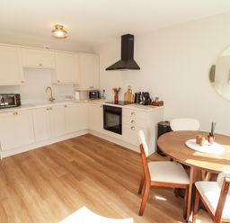 A kitchen with cabinets and dining table at Flat 4 in Tenby