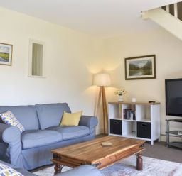 A living room with a sofa, table, and TV at The Hayloft in Hexham
