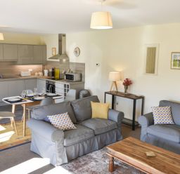 A living room with a sofa, coffee table, and kitchen area at The Hayloft in Hexham
