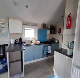 A kitchen with sink and stove at Lyons Sunnysands - Snowdon Summit 050 Talybont