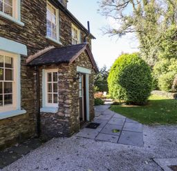 An outdoor view of a stone wall and pathway at Jessicas Cottage in Windermere
