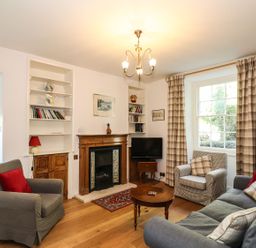 A living room with a fireplace and bookshelf at Jessicas Cottage in Windermere