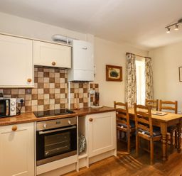 A kitchen with cabinets and a dining table at Jessicas Cottage in Windermere