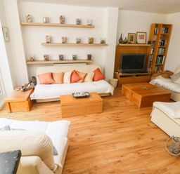 A living room with a sofa, coffee table, and television at Basement Apartment in Tenby