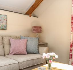 A living room featuring a sofa with cushions and a vase with flowers at Oak Cottage in Truro