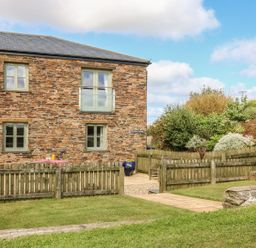 A garden with a stone building and wooden fence at Hawthorn Cottage in Truro
