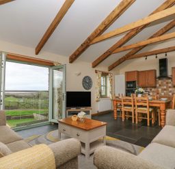 A living room with a sofa and dining area at Hawthorn Cottage in Truro