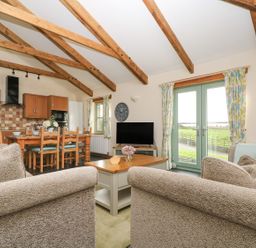 A living room with a sofa and dining area at Ash Cottage in Truro