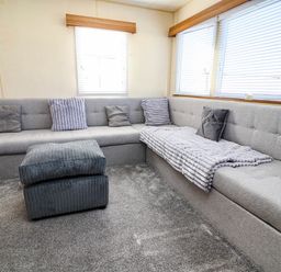 A living room with a sectional sofa and ottoman at Beach Fields 45 in Kinmel Bay