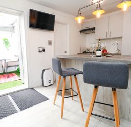 A kitchen with bar stools and a television at Flat 1, 2 Wooperton Street Weymouth