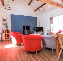 A living room with red and grey sofas and a television at Hen Blas in Pwllheli