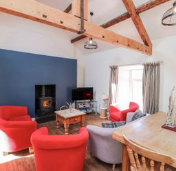 A living room with a sofa, chairs, and a fireplace at Hen Blas in Pwllheli