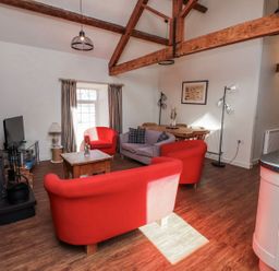 A living room with a sofa, armchairs, and a table at Hen Blas in Pwllheli
