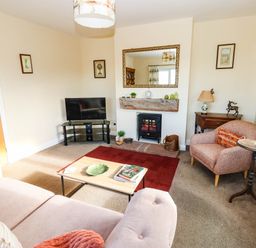 A living room with a sofa, armchair, and television at The Bungalow in Penrith