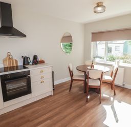 A kitchen with an oven and a table with chairs at Flat 2 in Tenby