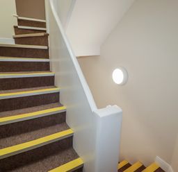 A staircase with carpeted steps and a light fixture at Flat 5 Tenby