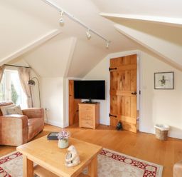 A living room with a television and sofa at High Beck Cottage in Kendal