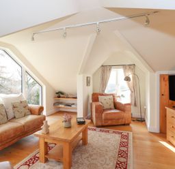 A living room with a sofa and armchair at High Beck Cottage in Kendal