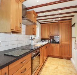 A kitchen with wooden cabinets and a stove at High Beck Cottage in Kendal