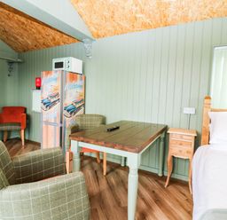 A sleeping area with a table and chairs at Calendonia Hut in West Mains near Haggerston