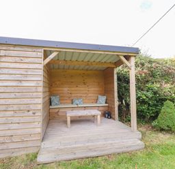 An outdoor seating area with a wooden cabin and bench at The Gables in Alnwick