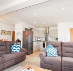 A living room with a sofa and kitchen in Apartment 3 Newquay