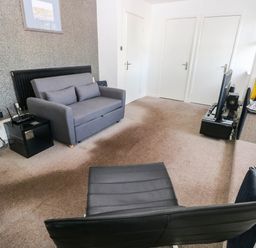 A living room with a sofa, television, and radiator at 21 Ferrara Square in Swansea