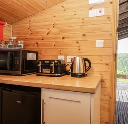 A kitchen with a microwave, toaster, kettle, and refrigerator at Thimble Lodge in Gunnislake