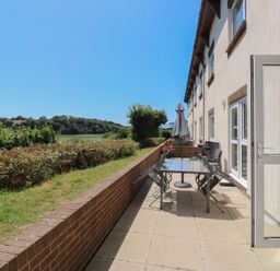 An outdoor seating area with a table and chairs at Willow in Kingsteignton