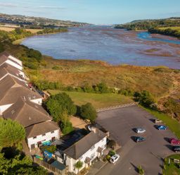 An aerial view of houses, a parking lot, and a river at Puffin in Kingsteignton