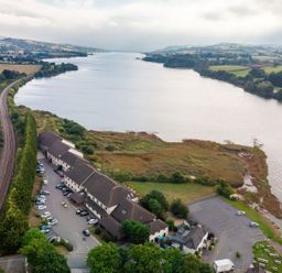 An aerial view of a river with buildings and greenery at Guillemot in Kingsteignton