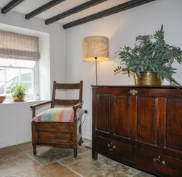 A room with a chair, a lamp, a plant, and a chest at Swn y Mor (Wexham) Beaumaris
