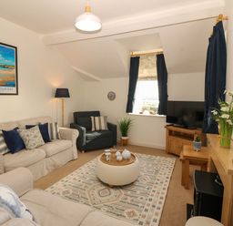 A living room with sofas, a television, and a window at Llywelyn in Trearddur Bay