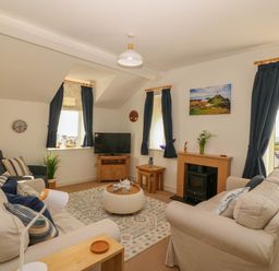 A living room with a television and sofa at Llywelyn in Trearddur Bay