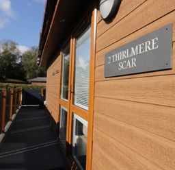 A wooden exterior with a sign and decking at Thirlmere Scar in Troutbeck Bridge