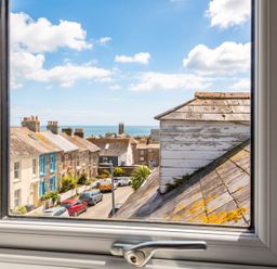 A view of houses and the sea from a window at seaside property