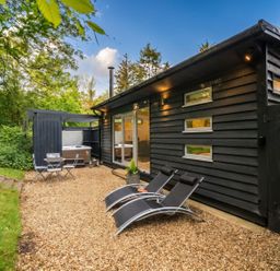 An outdoor area with chairs and a hot tub at a cabin in the woods