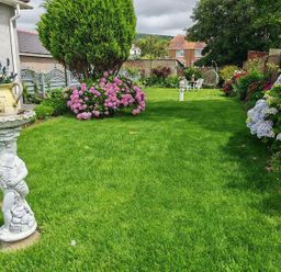 A garden with flowers and a stone statue at The Old Barn in Manchester