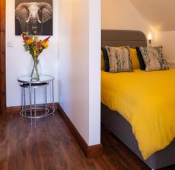 A bedroom with a yellow bedspread and a vase of flowers at Limavady Cherry Tree Apartment, Sleeps 2 and Parking Limavady