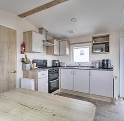 A kitchen with appliances and dining table at Ty dee seaview escapes in Looe