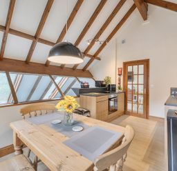 A kitchen with wooden beams and a dining table at 2 Bed, Sleeps 4 with Parking and EV charging in Wadebridge