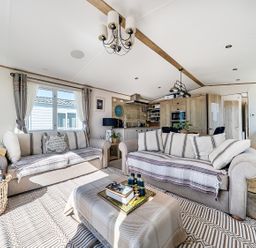 A living room featuring a sofa, coffee table, and kitchen unit at 2 Bed Caravan, Sleeps 4 with Sea Views in West Lulworth