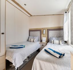 A bedroom with twin beds and a nightstand at 2 Bed Caravan, Sleeps 4 with Sea Views West Lulworth