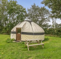 A yurt with a wooden door and a picnic table at Yurt, Sleeps 2 with BBQ and Fire Pit, Tregooden Farm near St Tudy