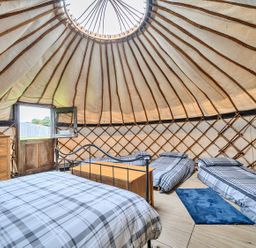A bedroom with beds and furniture in a Yurt, Sleeps 5 and Dogs Welcome