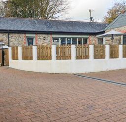 An exterior view of a stone building with a fence and umbrella at The Old Dairy in 